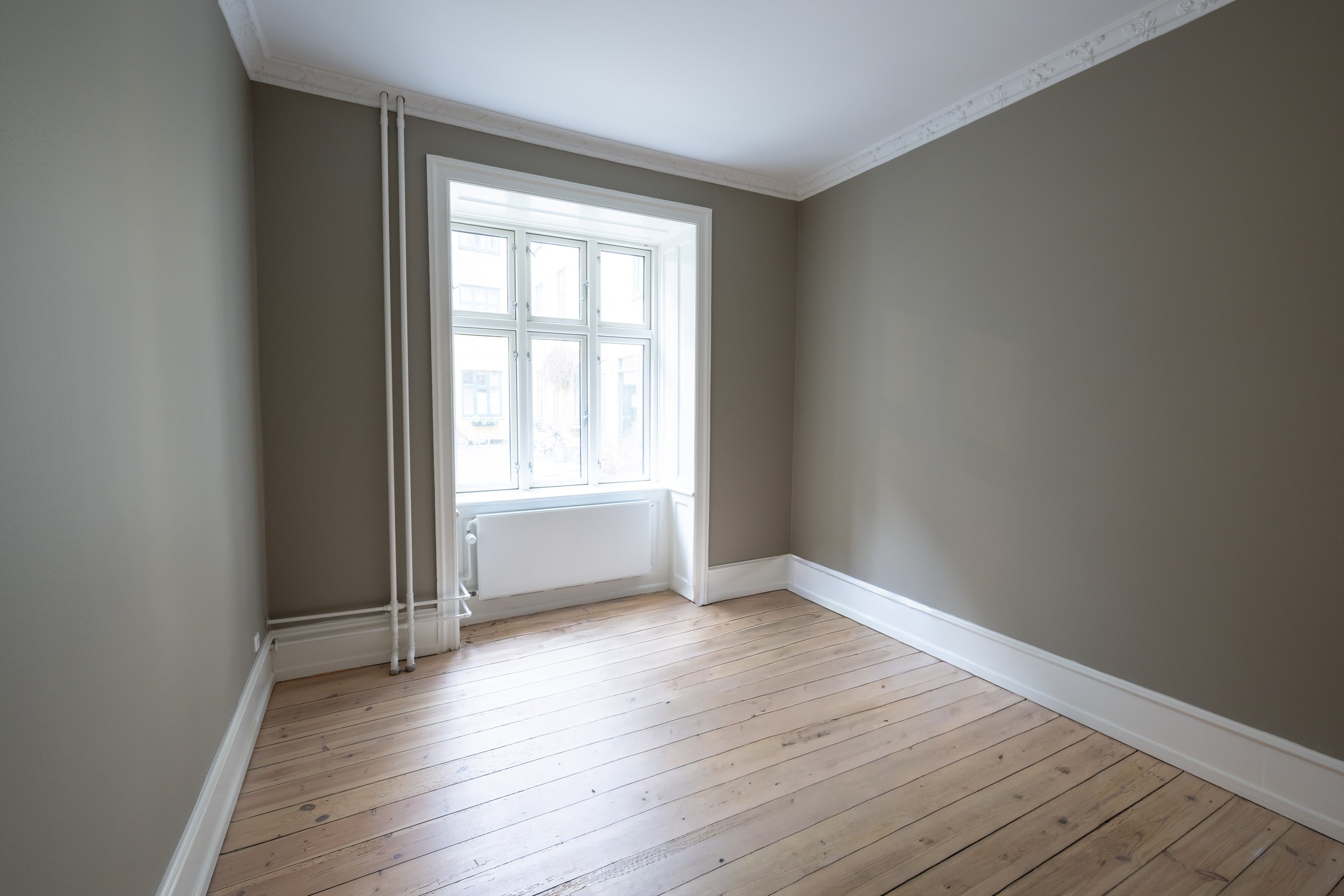 Værelse med loftsprofil og lyst plankegulv