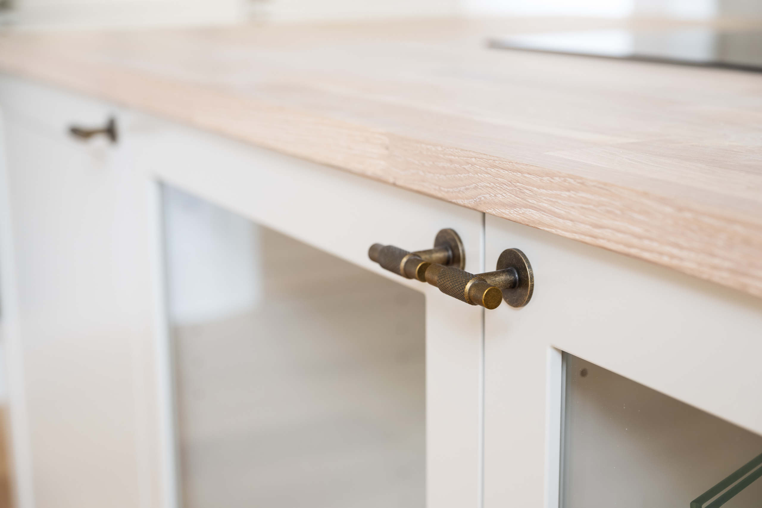 Detalje af køkkengreb, glasfronter og træbordplade