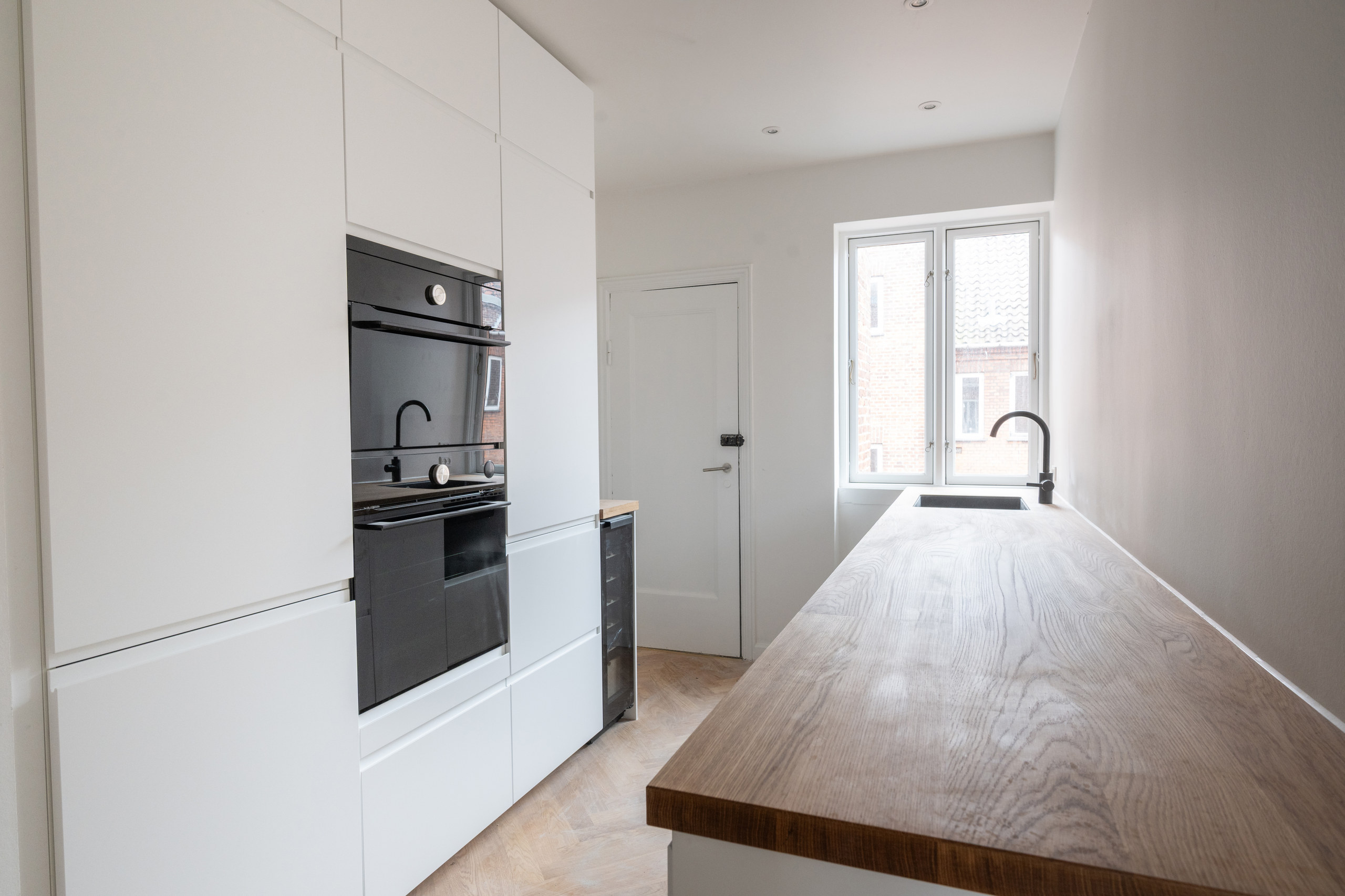 Langt, lyst køkken efter totalrenovering