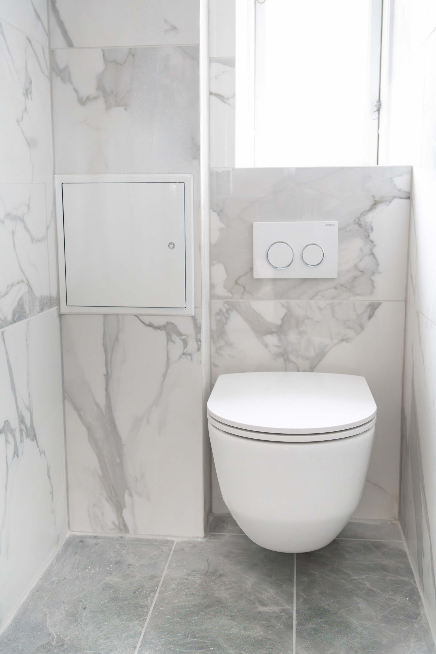 Væghængt toilet med marmormønstrede fliser