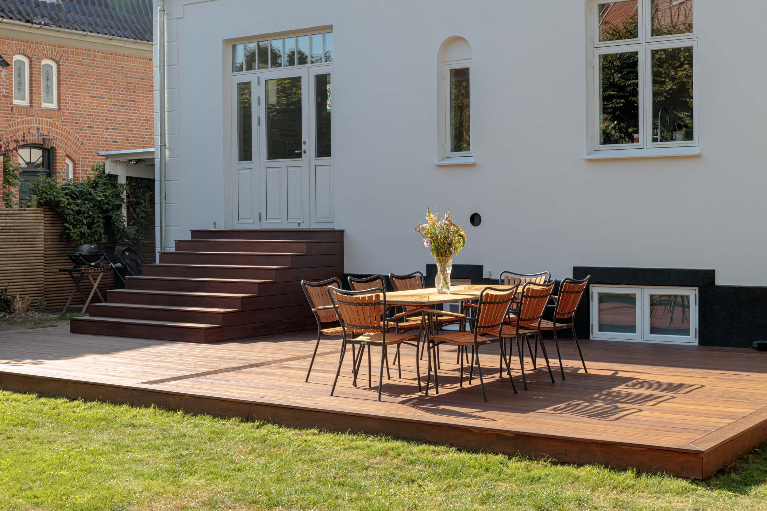 Træterrasse med spiseplads ved villaens havefacade